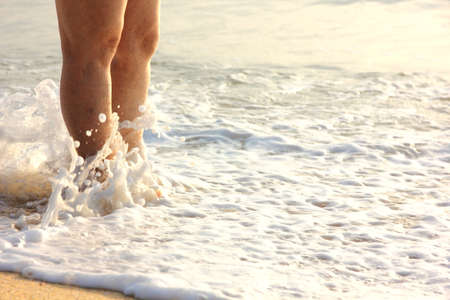 woman stand on beach waiting wave impact her legsの写真素材