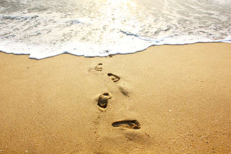 footprints on sand beach before the sea erasesthem