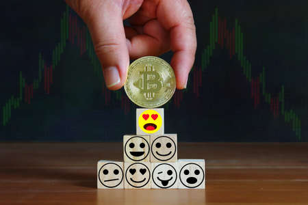 hand put on bitcoin on top of wood cube with illustration emotion  , bitcoin concept
