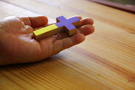 The Ukraine national flag color on wood cross on hand , save Ukraine war concept