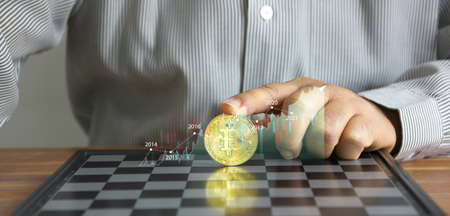 business hand put on index finger on bit coin on chess board with info graphic bit coin trend , bit coin idea conceptの写真素材