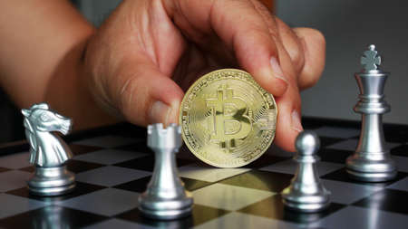 hand holding bitcoin on chess boeard , bitcoin conceptの写真素材