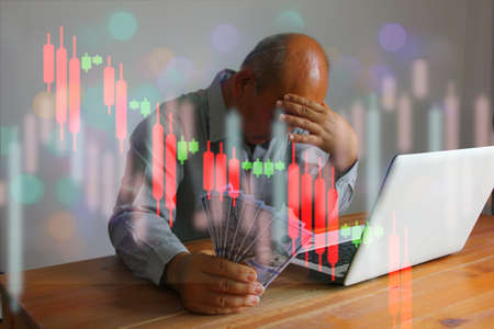 senior finansier holding dollar in hand working with laptop in sad moment with info graphic trend graphの写真素材