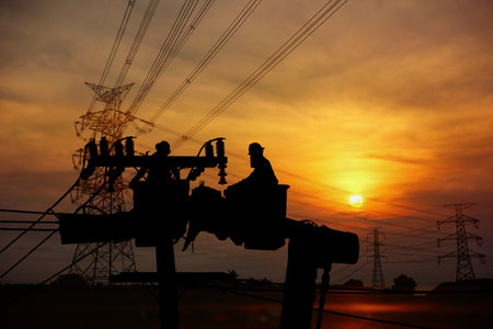 silhouette group of electrician workers working load on crane and lamp post on sun set sky nature backgroundの写真素材