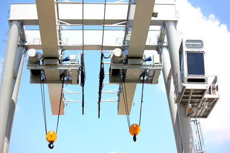 close up low angled shot outdoor two eletric hoists moter set on beam with crane control room against blue skyの写真素材
