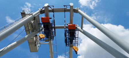 close up low angled shot outdoor two eletric hoists moter set on beam against blue skyの写真素材
