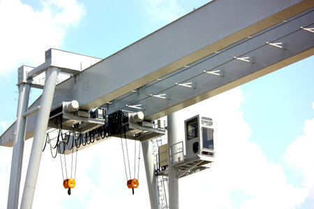 close up low angled shot outdoor two eletric hoists moter set on beam with crane control room against blue skyの写真素材