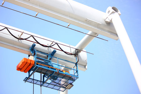 close up low angled shot outdoor electric hoist motor set on beam against blue skyの写真素材