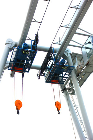 close up low angled shot outdoor two electric hoists motor set on beam against blue skyの写真素材
