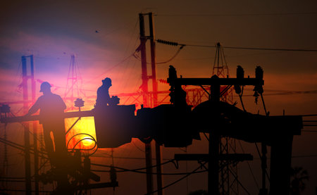 group of silhouette electric worker working on pole connected high voltage transmission line with  high voltage transmission towersの写真素材