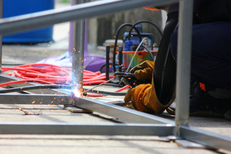 close up welder  welding  steel structure in construction site . welder put on leather gloves and...