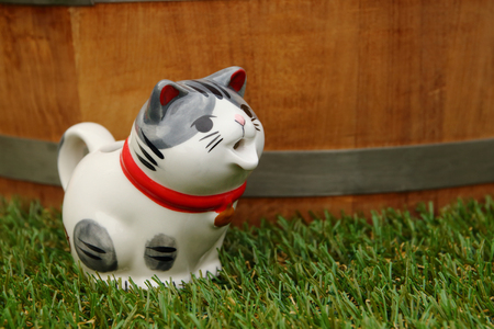 cat figurine on artificial grass and wooden bucket for backgroundの写真素材