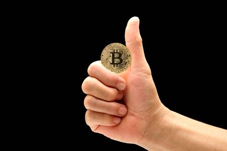 man hand in good symbol to holding bitcoin isolated on black backgroundの写真素材