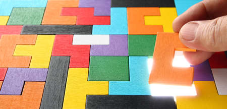 man hand holding a jigsaw puzzle piece on colorful jigsaw puzzle background , business concept