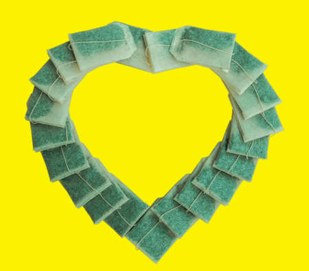 Healthy tea bags arranged in a heart shape on a yellow backgroundの写真素材