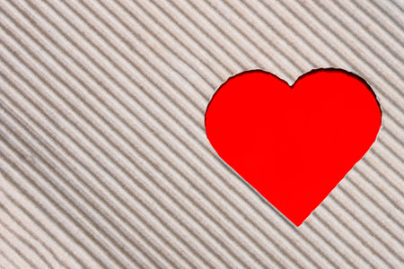 corrugated paper cut in a heart shape on red backgroundの写真素材