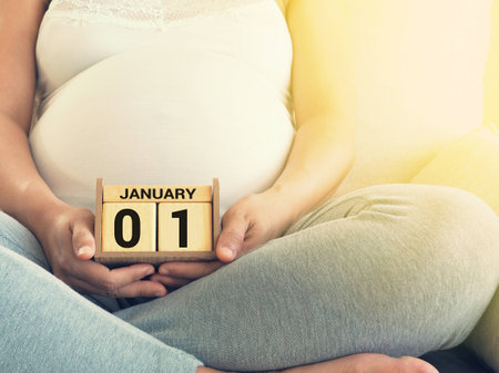 Baby's due date on a calendar with pregnant woman background. Maternity concept. Expecting an upcoming baby. Due date countdown.の写真素材