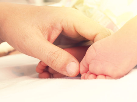 Mother hand touch on the newborn baby feet. Concept of warm and happy family.の写真素材