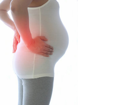 Pregnant woman with back pain isolated on white background. Concept of pregnancy healthcare.の写真素材