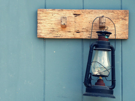 Burning kerosene lamp hang on the wooden wall. Home decoration by old lamp in vinage style.の写真素材