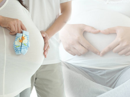 Pregnant woman and her husband. Mom is holding new born baby socks. Concept of pregnancy health care.の写真素材