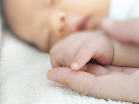 Close up hand of sleeping baby in the hand of mother.の写真素材