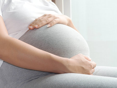 Close-up of pregnant woman with hands over tummyの写真素材