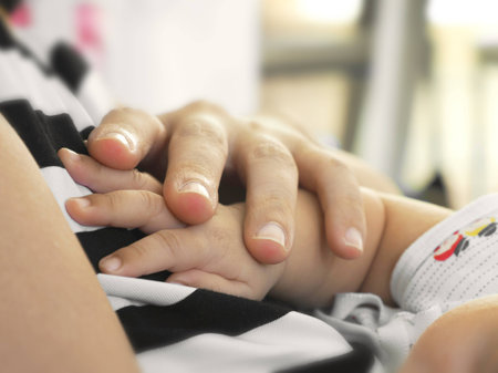Mother hold newborn baby hand over her breast. Concept of love and family.の写真素材