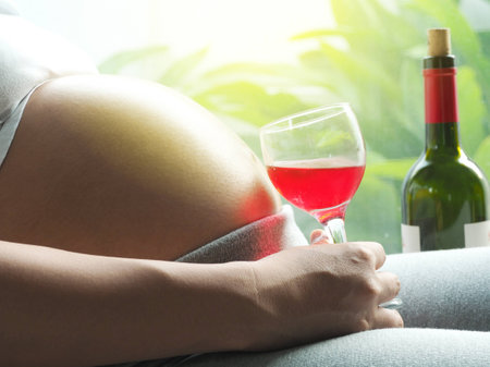 Pregnant woman with glass of wine in hand. Concept of pregnancy health care.の写真素材