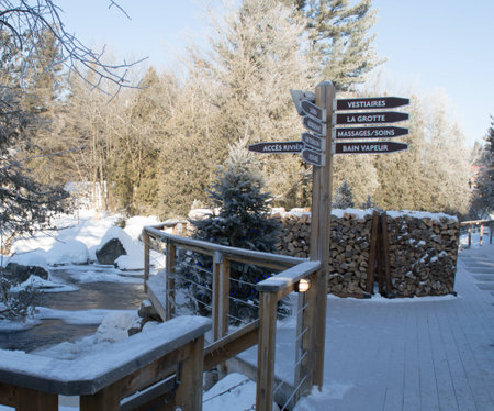 winter picture, deck piled with fire wood reserves, running river and sign post for a spa 