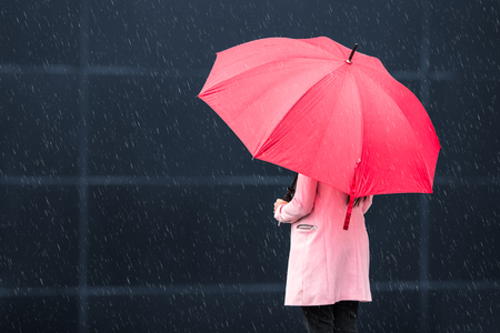 Girl with red umbrella on rainy dayの写真素材