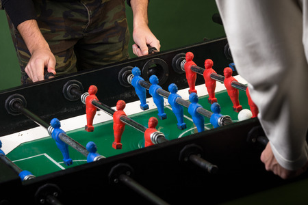 Two man playing foosball table game