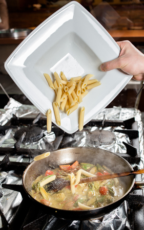 Penne Pasta with vegetables in panの写真素材