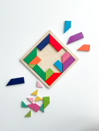 tangram game. Multicolored parts are disassembled on white table. top view