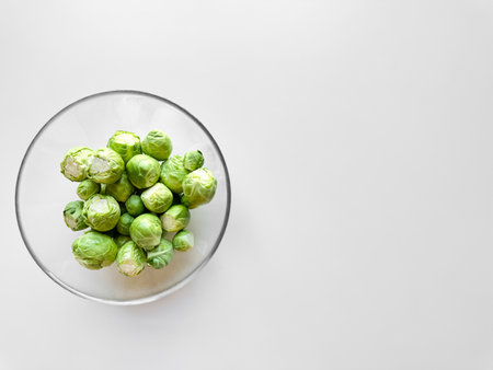 Brussels sprouts in transparent glass bowl on white background with ample space for text, healthy food concept.の写真素材