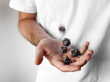 Close-up of person tossing polyhedral dice against a white background