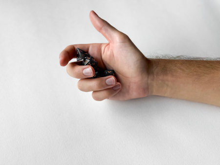Hand holding black polyhedral dice for tabletop gaming on white backgroundの写真素材
