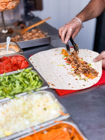 Chef preparing fresh shawarma wrap with vibrant vegetables in kitchen setting