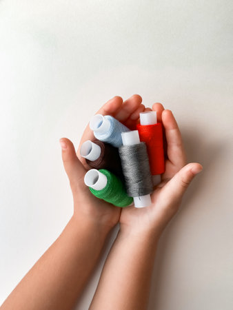 Hands holding colorful thread spools for sewing and crafting creativity