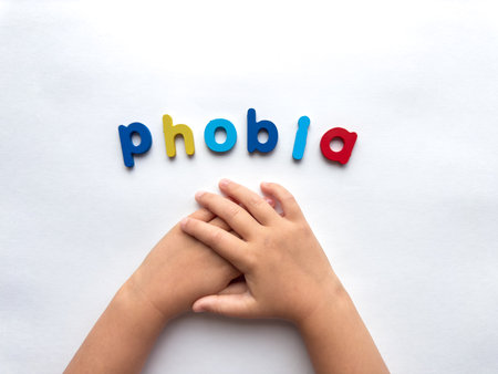 Childrens hands holding in anxiety concept with colorful phobia letters on white backgroundの写真素材