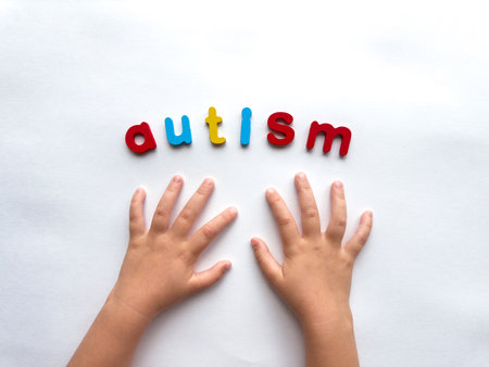 Childs hands and colorful letters spelling autism on white backgroundの写真素材