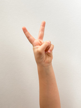Peace gesture with childs hand on simple white backgroundの写真素材