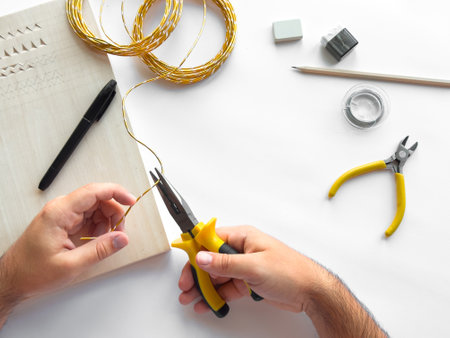 Hands crafting diy jewelry with wire and tools on white backgroundの写真素材