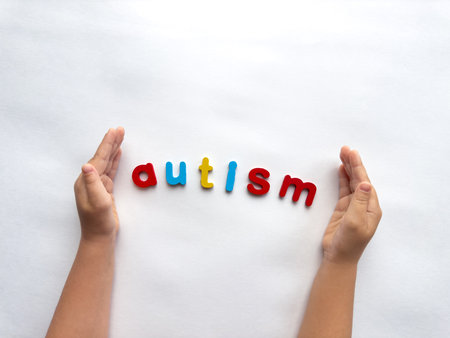 Hands framing colorful letters spelling autism on white backgroundの写真素材