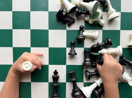Childrens hands arranging chess pieces on green and white boardの写真素材