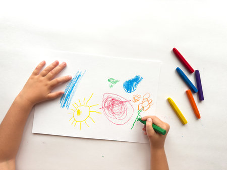 Childs colorful crayon drawing with bright sun, flowers, and geometric shapes on white paperの写真素材