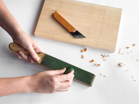 Hands sharpening tool with strop next to cutting board and carving knife