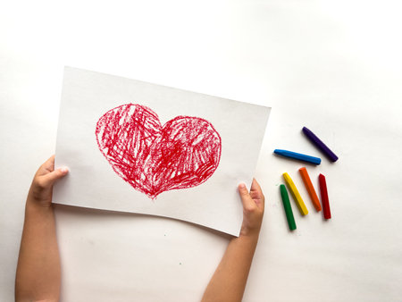 Childs colorful heart drawing with crayons on white backgroundの写真素材