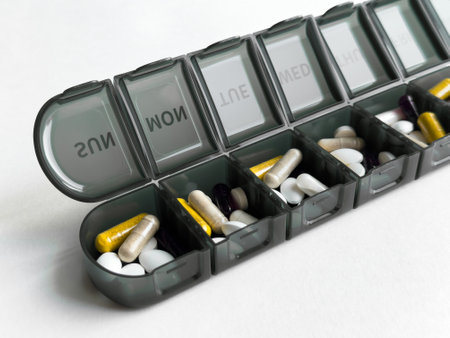 Weekly pill organizer with various vitamins and tablets on white backgroundの写真素材