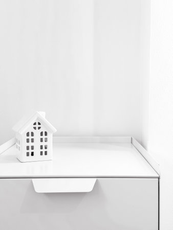 Minimalist white house model on a white shelf with bright lightingの写真素材